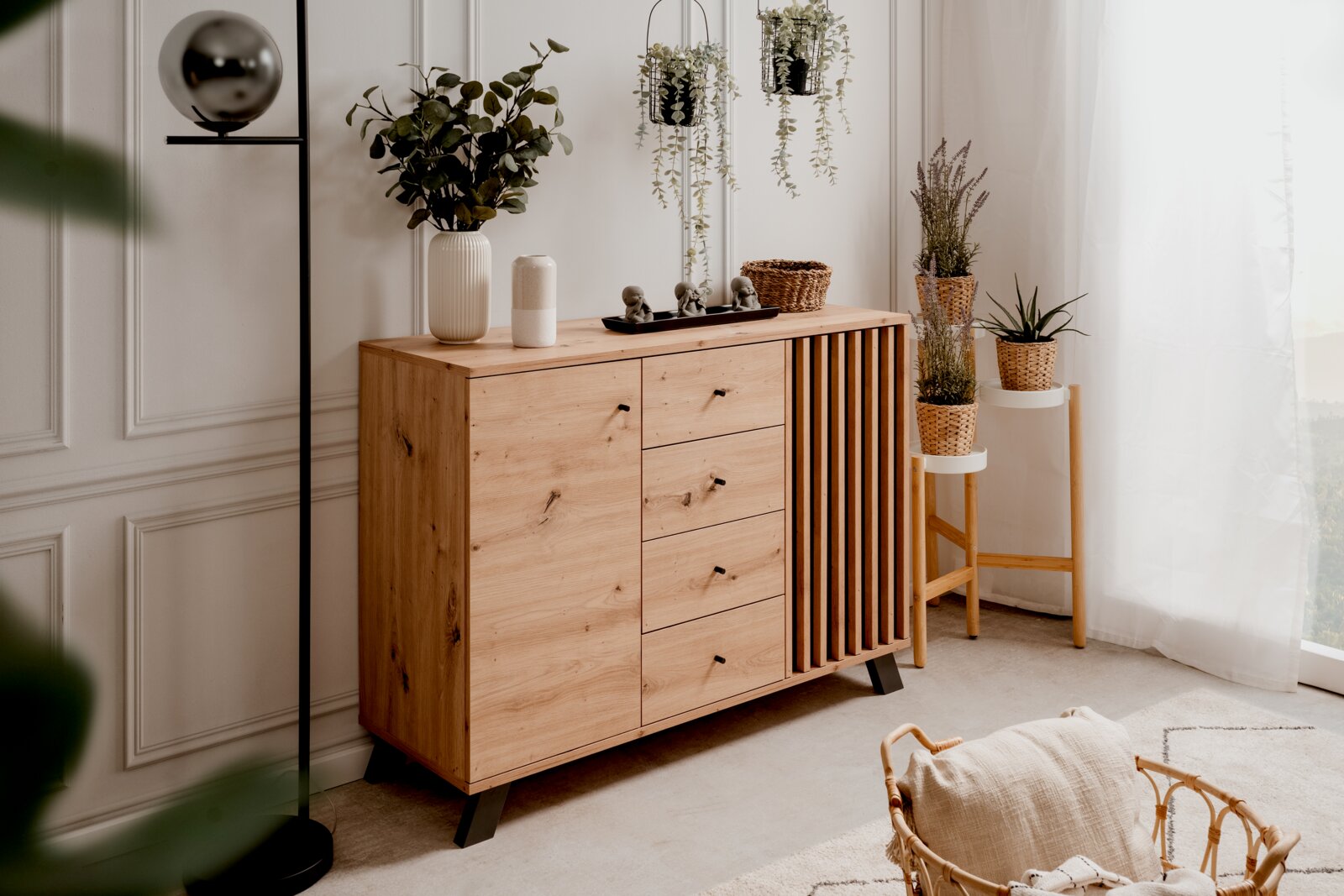 Holzkommode mit Schubladen und Lamellentür, dekoriert mit Pflanzen und Accessoires, seitliche Perspektive