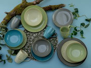 Vogelperspektive auf ein 16-teiliges Kombiservice-Set 'Nature' in verschiedenen Grüntönen, bestehend aus Tellern, Schalen und Tassen, dekoriert mit Moos und Zweigen.