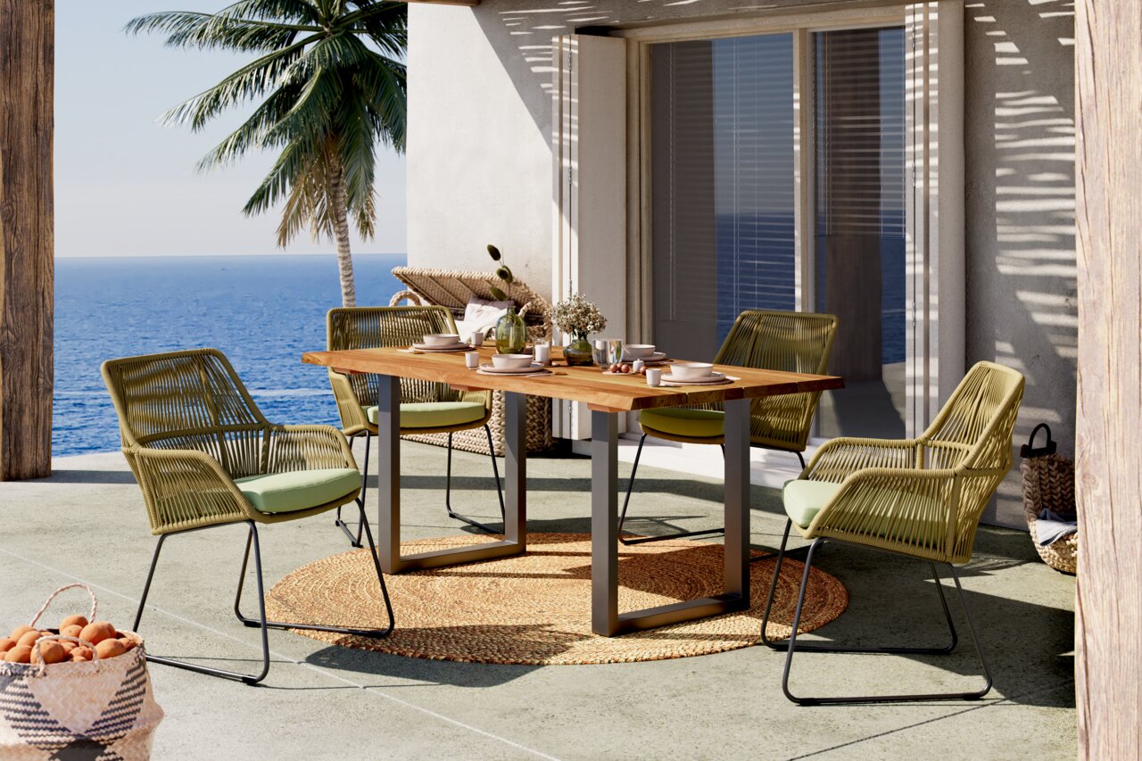 Moderner Gartensessel aus geflochtenem Material mit grünem Kissen, auf einer Terrasse mit Meerblick, von vorne betrachtet.