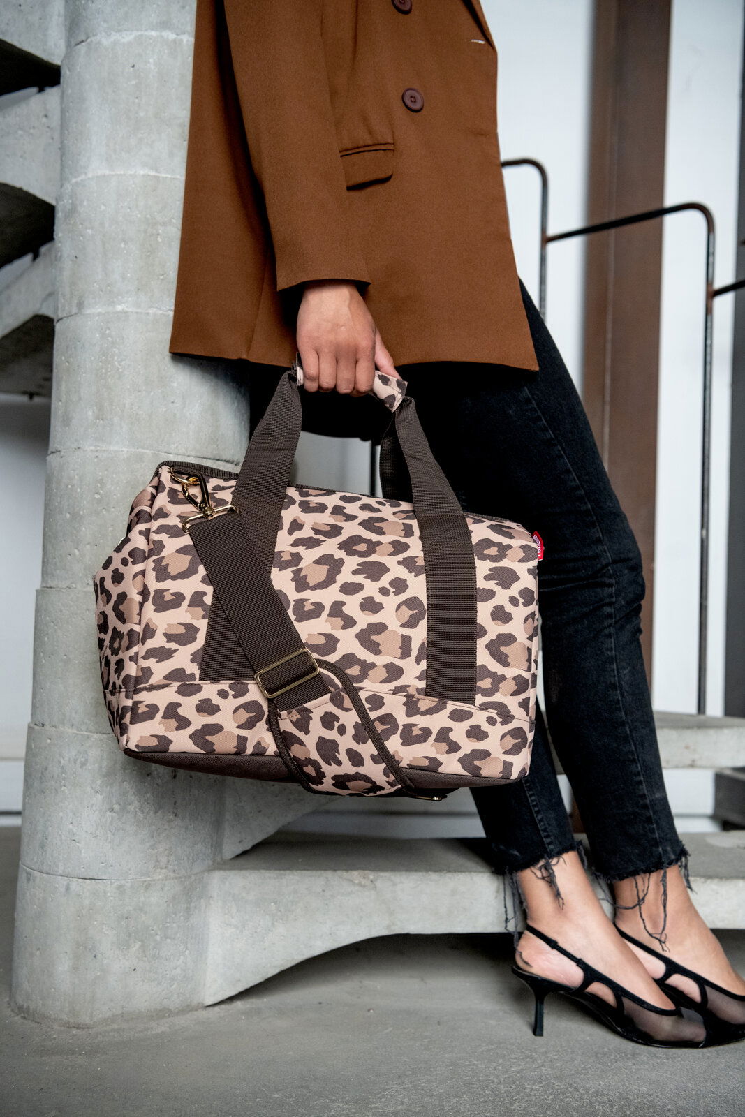 Leopardenmuster-Tasche in Macchiato-Farbe, getragen von einer Person in einem braunen Blazer und schwarzen Jeans, seitliche Perspektive.