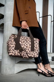 Tas met luipaardprint in de kleur macchiato, gedragen door iemand in een bruine blazer en een zwarte spijkerbroek, gezien vanaf de zijkant.