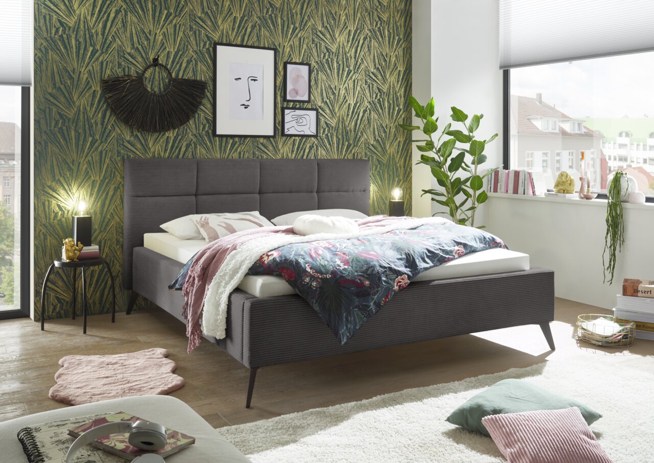 Modernes Polsterbett in einem stilvoll eingerichteten Schlafzimmer, seitliche Perspektive