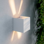 Moderne LED-Wandleuchte in kubischer Form, an einer Wand montiert, mit Lichtstrahlen nach oben und unten, seitliche Perspektive.