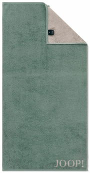 Grünes Duschtuch mit beiger Rückseite und JOOP!-Logo in der unteren rechten Ecke, aus der Vogelperspektive fotografiert.