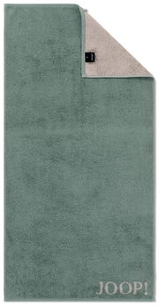 Grünes Duschtuch mit beiger Rückseite und JOOP!-Logo in der unteren rechten Ecke, aus der Vogelperspektive fotografiert.