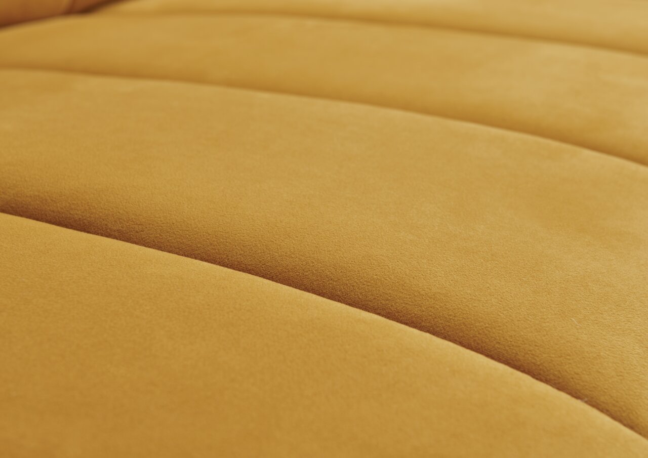 Close-up van een gele, ronde hoekbank met een zachte, fluweelachtige textuur.