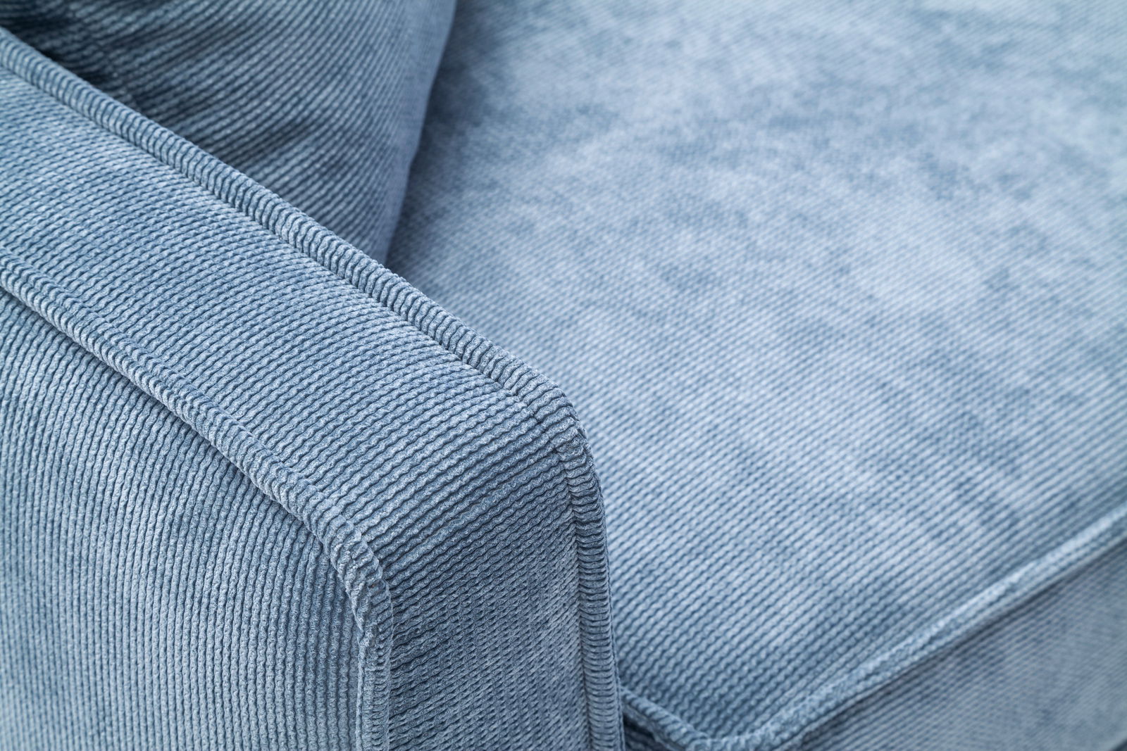 Nahaufnahme eines blauen Funktionssofas mit strukturiertem Stoffbezug, Blick auf die Armlehne und Sitzfläche.