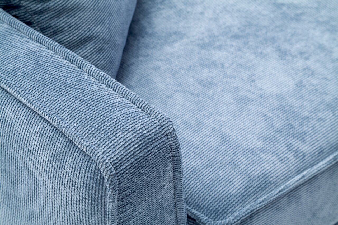 Nahaufnahme eines blauen Funktionssofas mit strukturiertem Stoffbezug, Blick auf die Armlehne und Sitzfläche.