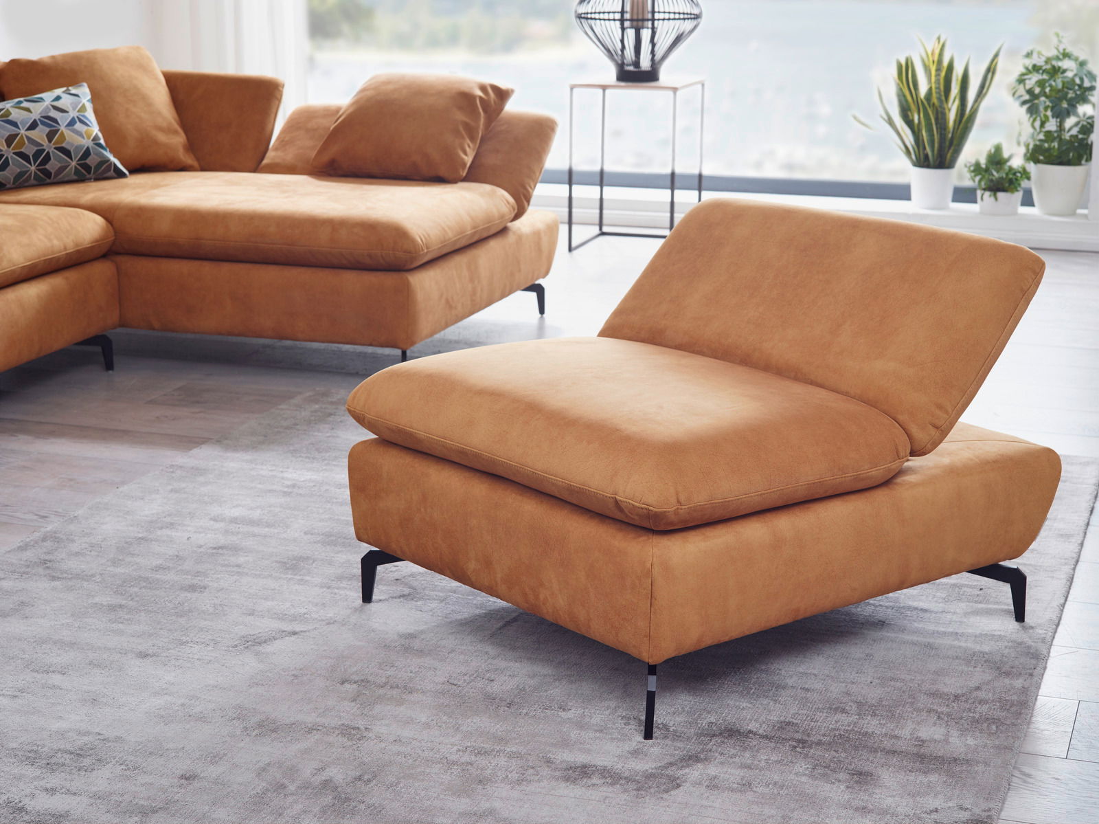 Moderner Funktionshocker in warmem Braunton, seitliche Perspektive, in einem stilvollen Wohnzimmer mit großen Fenstern und Pflanzen.