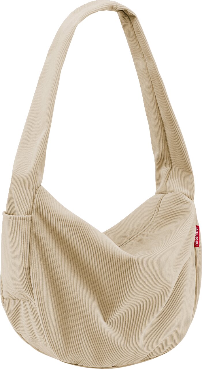 Beige corduroy schoudertas met brede schouderriem en rood reisenthel-label aan de zijkant, vrijstaand op een witte achtergrond, vooraanzicht licht van opzij
