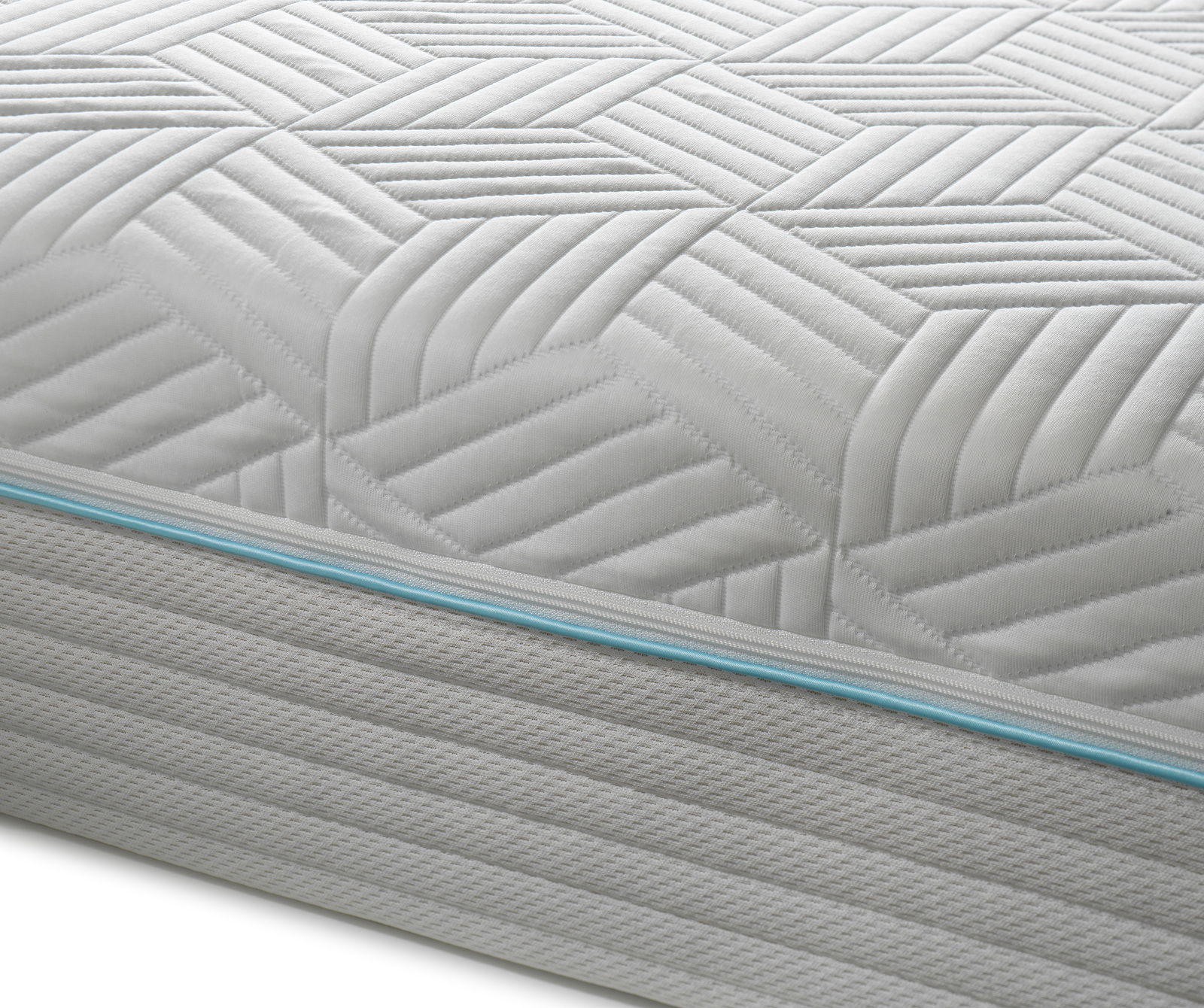 Nahaufnahme einer Gel-Kaltschaummatratze mit geometrischem Muster und blauer Ziernaht, seitliche Perspektive.