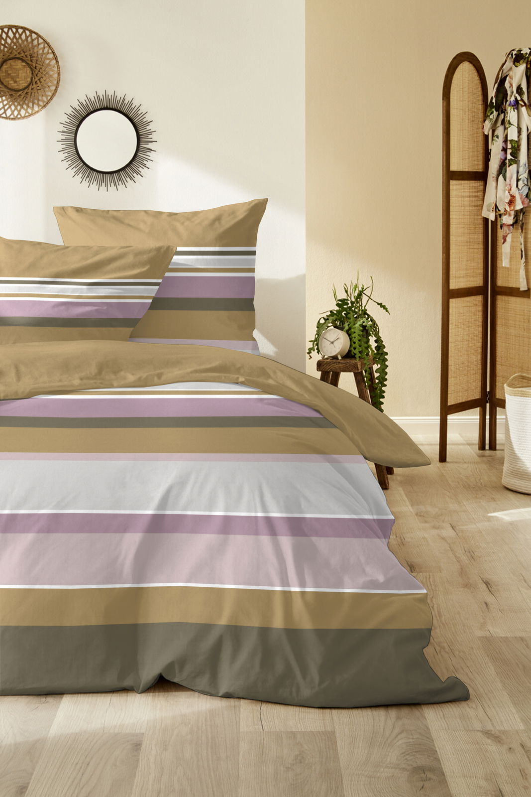 Bettwäsche-Set mit Streifenmuster in Beige, Lila und Weiß, auf einem Bett in einem gemütlichen Schlafzimmer mit Holzboden und Dekorationen, aus der Vorderansicht fotografiert.