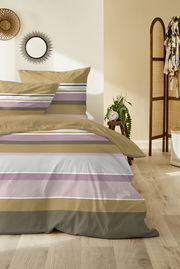 Bettwäsche-Set mit Streifenmuster in Beige, Lila und Weiß, auf einem Bett in einem gemütlichen Schlafzimmer mit Holzboden und Dekorationen, aus der Vorderansicht fotografiert.