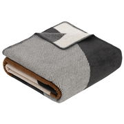 Gefaltete Jacquard Decke in Grautönen mit geometrischem Muster, seitliche Perspektive