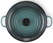 Obere Ansicht einer runden, türkisfarbenen Servierpfanne mit zwei Griffen und einem schwarzen Knauf auf dem Deckel.