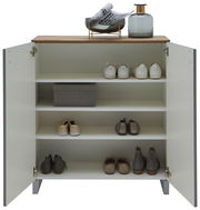 Offener Schuhschrank mit vier Regalböden, gefüllt mit Schuhen und einer Aufbewahrungsbox, aus der Frontperspektive fotografiert. Auf der Oberseite befinden sich eine Vase und Zeitschriften.