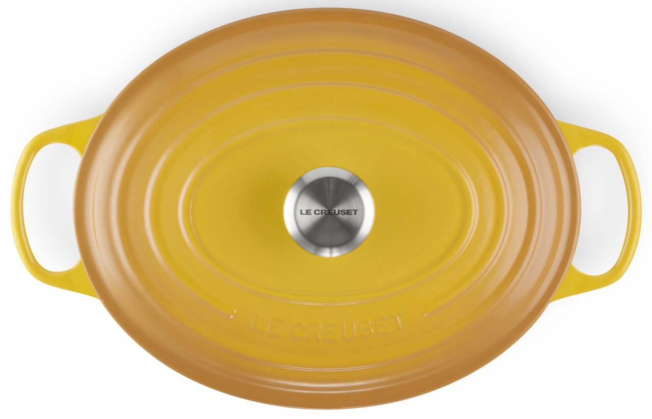 Gele ovale braadpan, gezien van bovenaf, met twee handvatten en een zilveren knop, van het merk Le Creuset