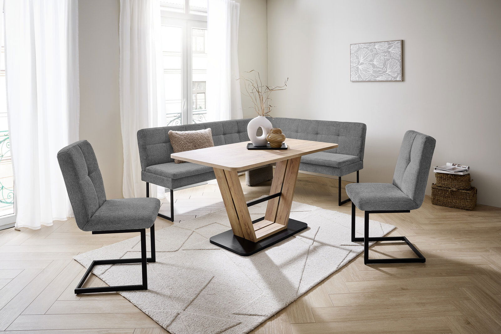 Moderne Esszimmer-Eckbankgruppe mit grauen Polstern und Holztisch in einem hellen Raum, seitliche Perspektive.