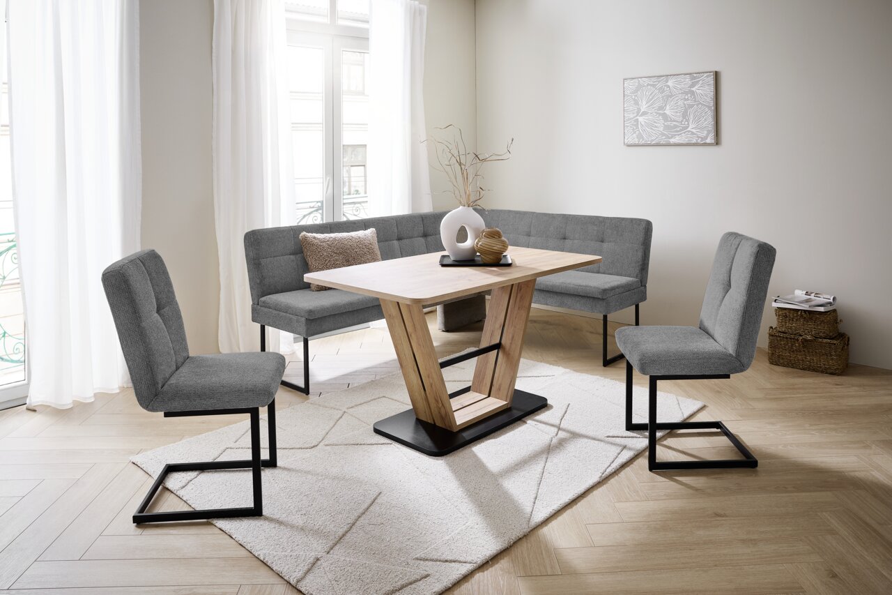 Moderne Esszimmer-Eckbankgruppe mit grauen Polstern und Holztisch in einem hellen Raum, seitliche Perspektive.