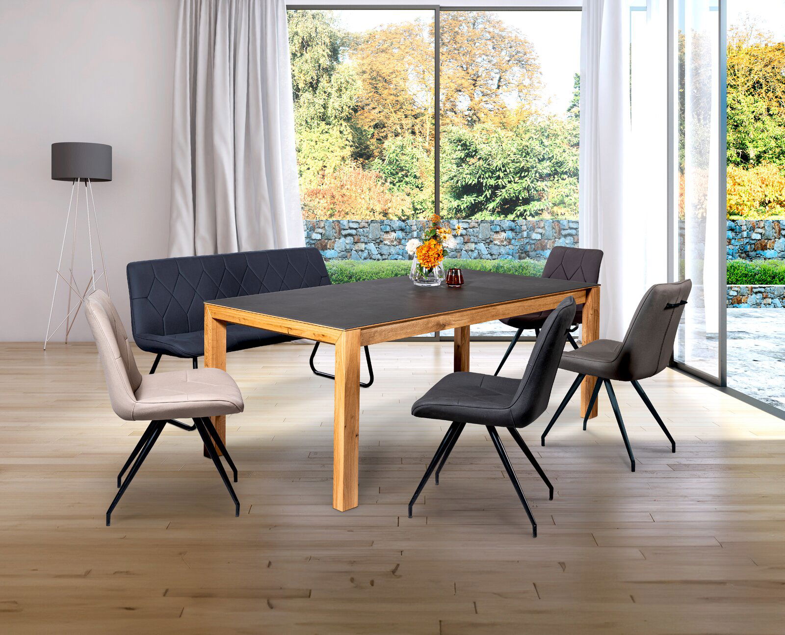 Novel Bank HENRY Esszimmer mit modernem Tisch und Stühlen in einem hellen Raum mit großen Fenstern, Blick von schräg vorne.