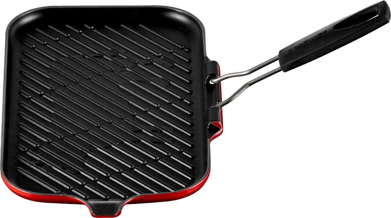Vierkante gietijzeren grillpan met ribbels, zwarte binnenkant en rode buitenrand, met lange handgreep schuin bovenaanzicht op witte achtergrond.