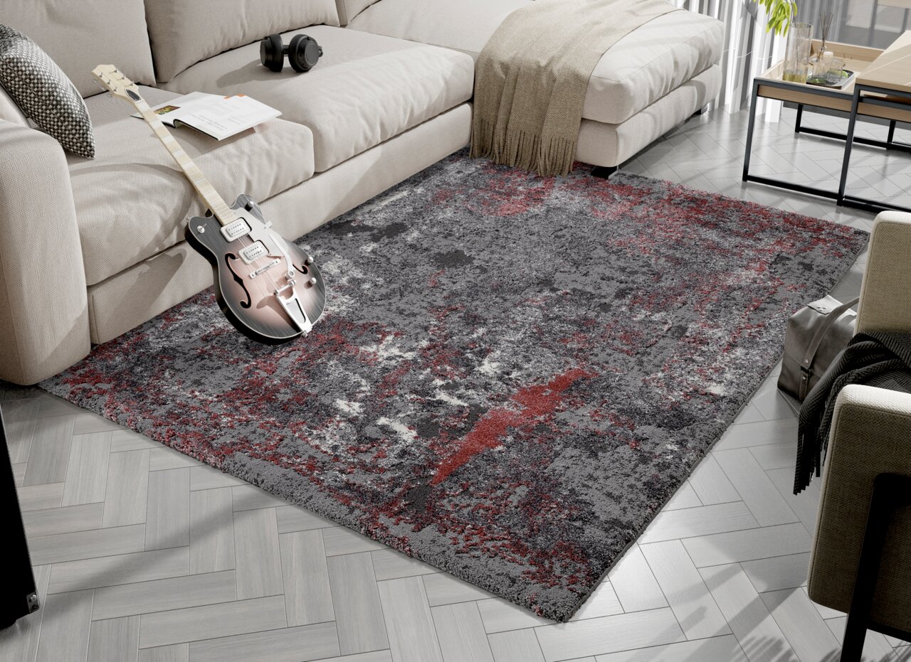 Designer Teppich in Grau- und Rottönen, platziert in einem modernen Wohnzimmer mit Sofa und Gitarre, aus der Vogelperspektive.