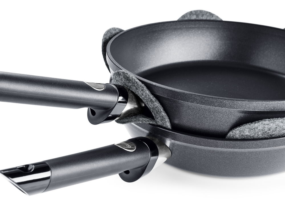 Fissler Pfannenschutz Set 2-tlg. Zwei übereinander gestapelte Pfannen mit grauen Filz-Pfannenschützern dazwischen, seitliche Perspektive