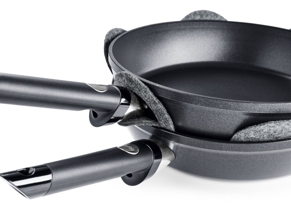 Fissler Pfannenschutz Set 2-tlg. Zwei übereinander gestapelte Pfannen mit grauen Filz-Pfannenschützern dazwischen, seitliche Perspektive