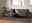 Moderner Couchtisch mit schwarzer Marmoroptik und Metallgestell, frontal vor einem grauen Sofa in einem stilvoll eingerichteten Wohnzimmer.