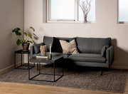 Moderner Couchtisch mit schwarzer Marmoroptik und Metallgestell, frontal vor einem grauen Sofa in einem stilvoll eingerichteten Wohnzimmer.