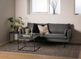 Moderner Couchtisch mit schwarzer Marmoroptik und Metallgestell, frontal vor einem grauen Sofa in einem stilvoll eingerichteten Wohnzimmer.