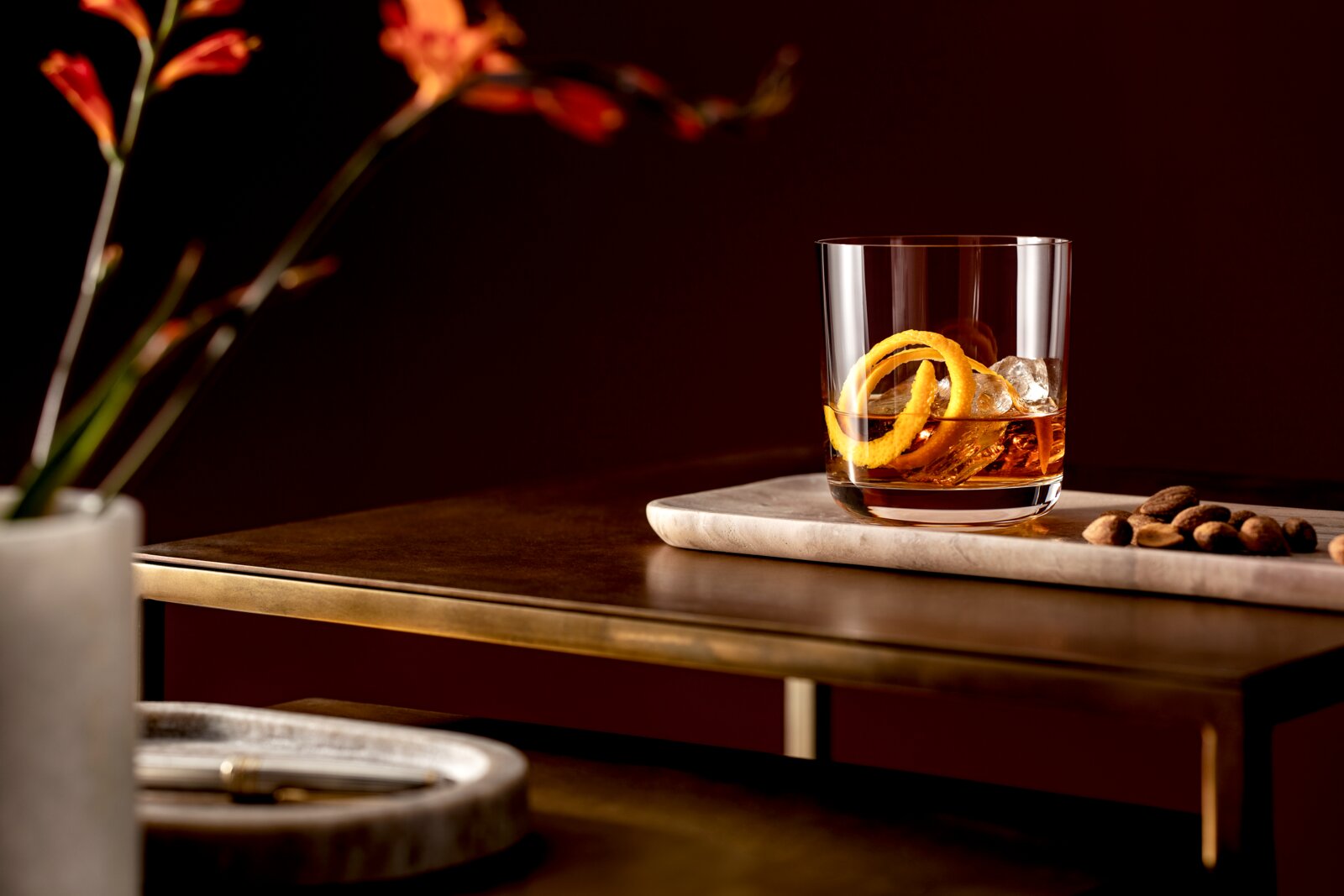 Villeroy & Boch Whiskybecher 4er-Set LA DAVINA Whiskyglas mit Eiswürfeln und Orangenschale auf einem Tisch, seitliche Perspektive
