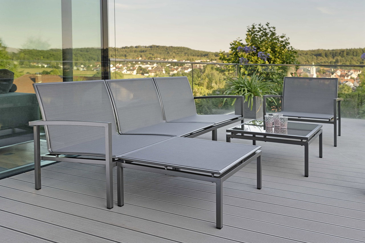 Moderne Outdoor-Lounge-Möbel auf einer Terrasse mit Blick auf die Landschaft, Perspektive von der Seite.