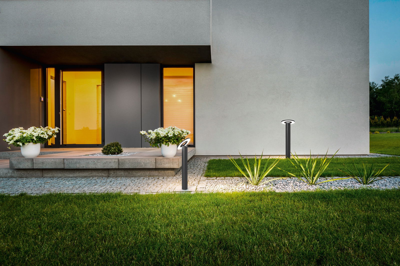 Moderne LED-Pollerleuchte von Fabas Luce im Garten eines Hauses, seitliche Perspektive.