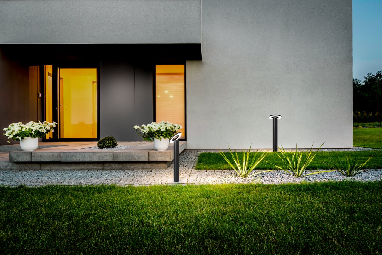 Moderne LED-Pollerleuchte von Fabas Luce im Garten eines Hauses, seitliche Perspektive.
