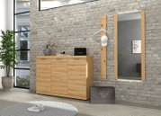 Moderne Garderobe im Flur: helles Holz-Sideboard mit drei Türen vor grauer Ziegelwand, daneben Wandspiegel und Garderobenpaneel mit Kleiderbügel und weißer Kappe, perspektivisch in leichter Schrägansicht von vorn.