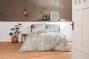 Bettwäsche-Set in einem stilvollen Schlafzimmer mit Pflanzen und moderner Dekoration, aus der Perspektive durch eine geöffnete Tür betrachtet.