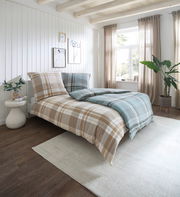 Gemütliches Schlafzimmer mit kariertem Bettwäsche-Set in Beige und Blau, seitliche Perspektive.