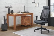 Moderner Schreibtisch aus Holz mit Schubladen, seitliche Perspektive, neben einem ergonomischen Bürostuhl in einem stilvollen Büro mit weißer Backsteinwand.