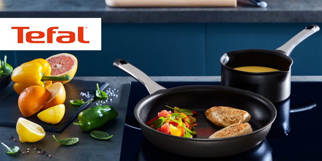 Schwarze Tefal-Pfanne und kleiner Topf mit Hähnchen und Gemüse