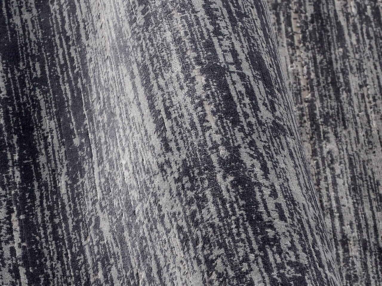 Nahaufnahme eines Designer Teppichs mit grauem und schwarzem Muster in diagonaler Perspektive.