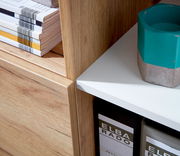 Nahaufnahme eines Aktenschranks mit Holzoptik, weißen Regalböden und darauf liegenden Zeitschriften. Perspektive von der Seite.