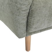 Nahaufnahme einer grünen Sofaecke mit Holzbein, Perspektive von der Seite.