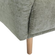 Nahaufnahme einer grünen Sofaecke mit Holzbein, Perspektive von der Seite.
