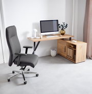 Hoekbureaucombinatie van hout met ingebouwde opbergruimte, afgebeeld vanuit een zijaanzicht. Er staat een moderne bureaustoel naast en op het bureau staat een computer met toebehoren.