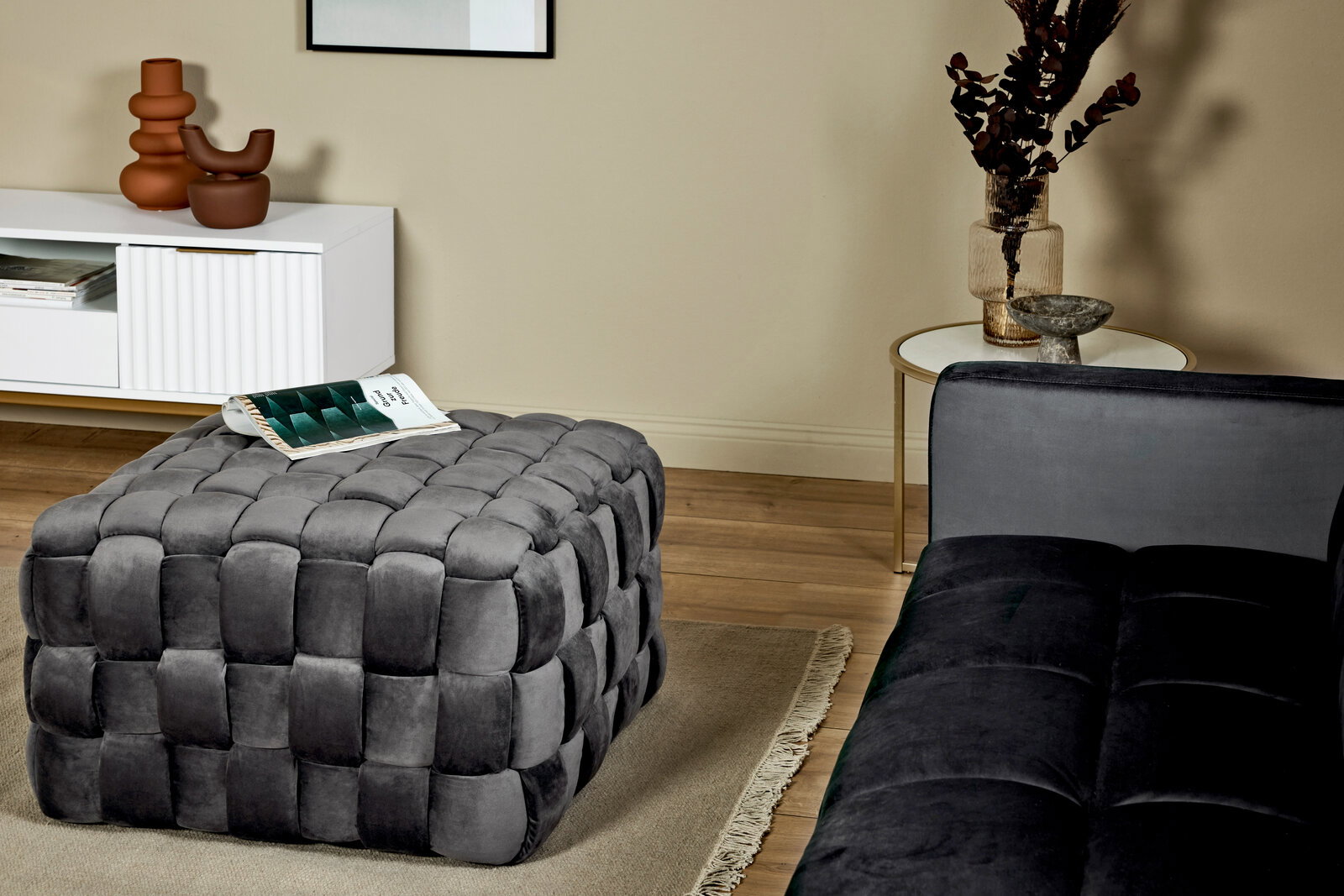 Grauer, gepolsterter Hocker in einem modernen Wohnzimmer, seitliche Perspektive