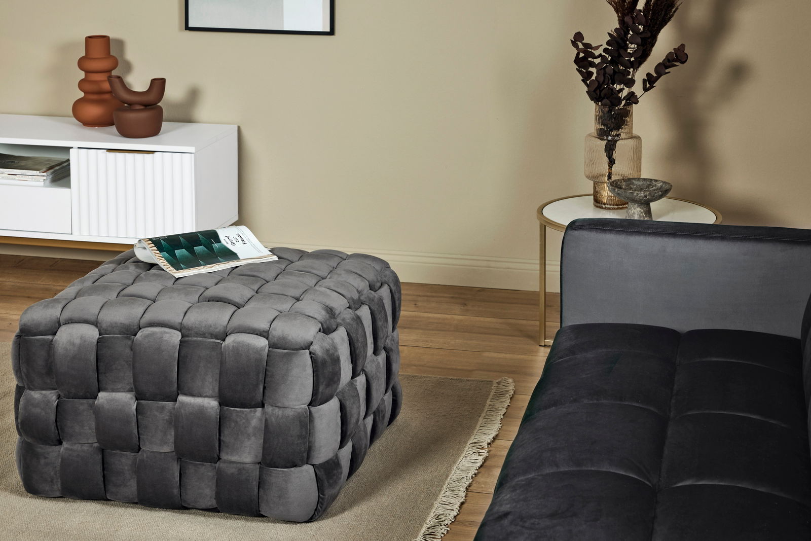 Grauer, gepolsterter Hocker in einem modernen Wohnzimmer, seitliche Perspektive