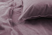 Nahaufnahme von lila Bettwäsche mit Kissenbezug, aus der Vogelperspektive fotografiert.