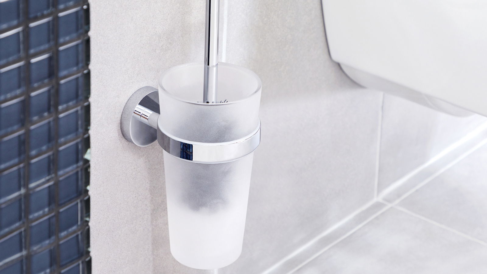 Wandmontierte WC-Bürste in einem matten Glasbehälter mit Chromhalterung, seitliche Perspektive