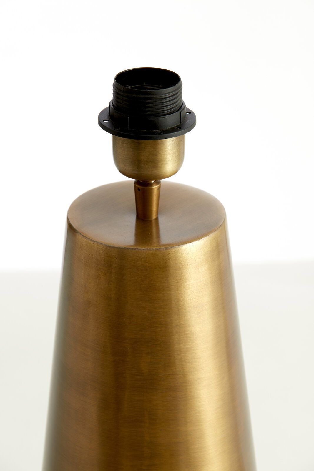 Nahaufnahme eines konischen Lampenfußes aus gebürstetem Metall mit einer schwarzen Lampenfassung, seitliche Perspektive.